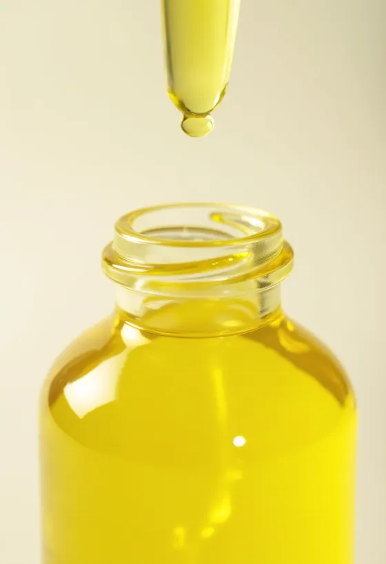 Sítrónuolía í lítilli flösku, við hliðina á ferskum sítrónusneiðum og rifnum berki