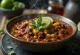Vegan chili með baunum í þykkri kryddsósu, skreytt með ferskum kóríander.